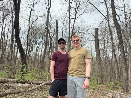 A photo of myself and my partner standing in the woods.