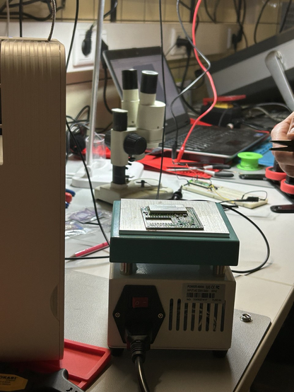 Eine Platine mit SMD-Bauteilen liegt auf einer Heizplatte