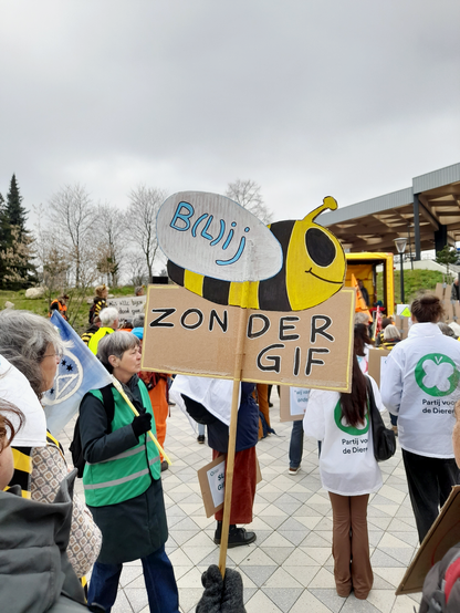 A protest sign showing a bee and the text "Happy without poison". There is one letter in parentheses so that it can also mean "Bee without poison".
