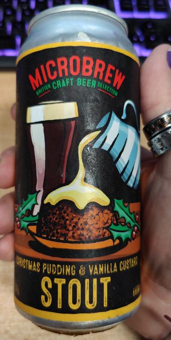 A can of beer. The label shows a Christmas pudding with custard being poured over it and in the back a glass of stout.
The text reads "Microbrew British Craft Beer Selection" and 'Christmas Pudding & Vanilla Custard Stout"