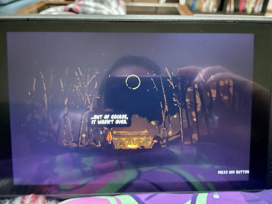 This screenshot shows the cutscene that plays after completing your first run. The prohibits is sitting at a campfire, and someone says, “…but of course, it wasn’t over.”