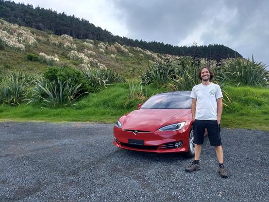 Grinning 7 year younger & hairier me in front of a very shiny Tesla