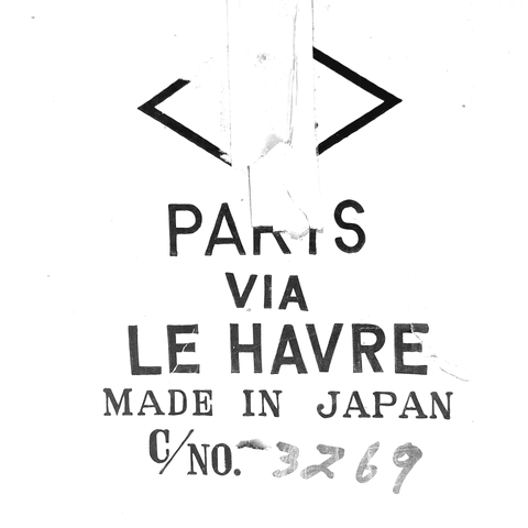 Monochrome picture derived from a photograph of a telescope box, featuring the text "PARIS VIA LE HAVRE" in sans serif letters (seemingly hand drawn after a model) and below "MADE IN JAPAN" in a serif contrasted style, letters are a bit irregular. At the bottom, there's a  catalog number.
