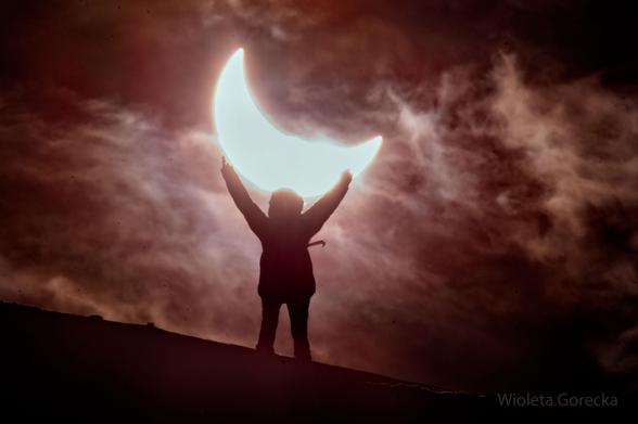 Person standing in front of a partial solar eclipse.