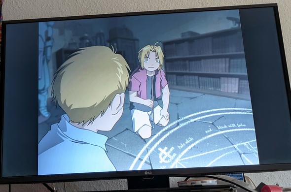 Fotografie meines Fernsehers. im 4 zu 3 Format zeigt er eine Szene aus einem Anime.

zu sehen sind die Charaktere Edward und Alphonse Erik aus dem Anime Fullmetal Alchemist oder aus dem Anime Fullmetal Alchemist Brotherhood. welche Adaption es hat verrate Ich nicht. Die beiden Brüder befinden sich gerade direkt vor einem Alchemisten Kreis. Beide sind noch Kinder