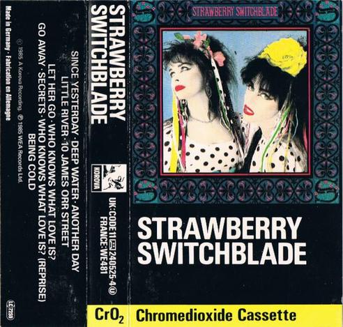 Outer sleeve of the Strawberry Switchblade pre-recorded cassette. There is the cover - a picture of two women in polka dots and ribbons with plastic flowers in their hair - and a bright yellow edge proclaiming that it's a chrome dioxide cassette