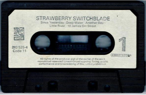 Side 1 of the Strawberry Switchblade album cassette. The title and track listing are in a faded dark grey print on a pale grey background.