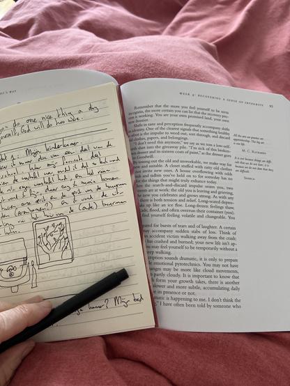 Een opengeslagen boek, met daarbij een opengeslagen en volgeschreven schrift. Boek en schrift liggen op een oud roze dekbed.