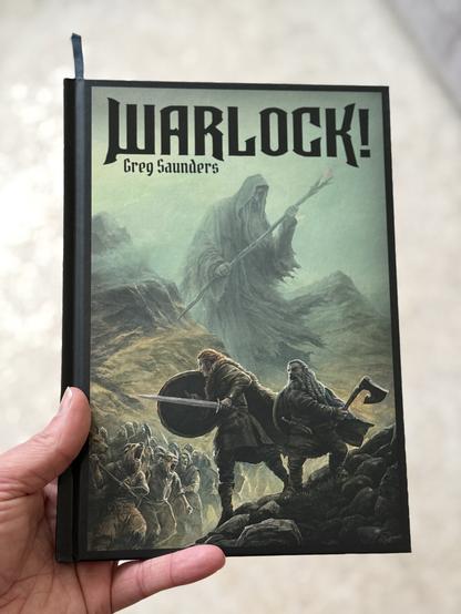 Cover eines Hardcover-Buchs  - zwei Bewaffnete mit Schild und Axt bzw. Schwert im Vordergrund stellen sich einer Übermacht von Tiermenschen. Im nebelhaften bergigen Hintergrund eine riesenhafte Gestalt in einer robe, Stab in der Hand. 

Titel :
WARLOCK!
Greg Saunders