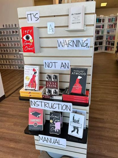 Books arranged in a library on display stand.
Notice saying: These books are a warning, NOT an instruction manual.
1984 - George Orwell 
Margaret Atwood - The Handmaid's Tale
Anne Frank - The Diary of a Young Girl 
On Tryanny - Timothy Snyder
Parabole of the Sower - Octavia Butler
Animal Farm - George Orwell 
Fahrenheit - Ray Bradbury