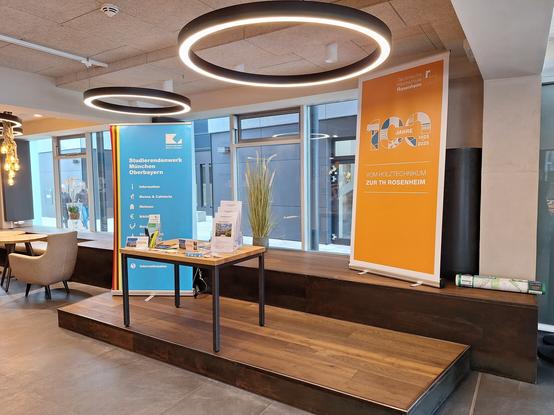 Infostand bestehend aus Roll-Up sowie Tisch mit Flyern und Give-Aways.