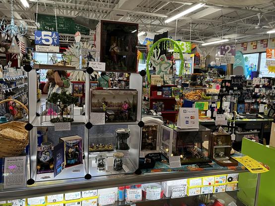 A counter full of assorted dioramas and miniature pieces for show and sale in a busy store.