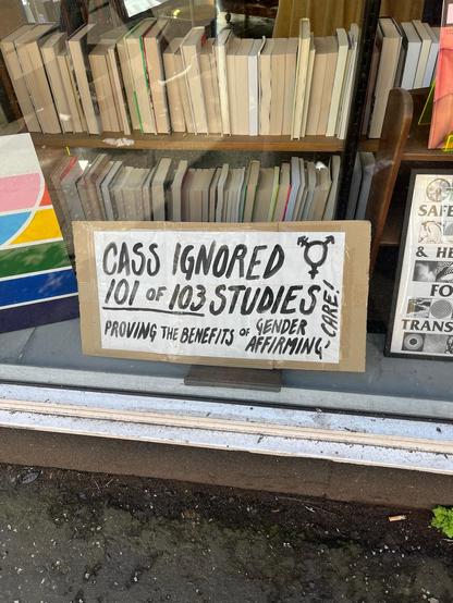 A sign "CASS IGNORED 101 OF 103 STUDIES PROVING THE BENEFITS OF GENDER AFFIRMING CARE"