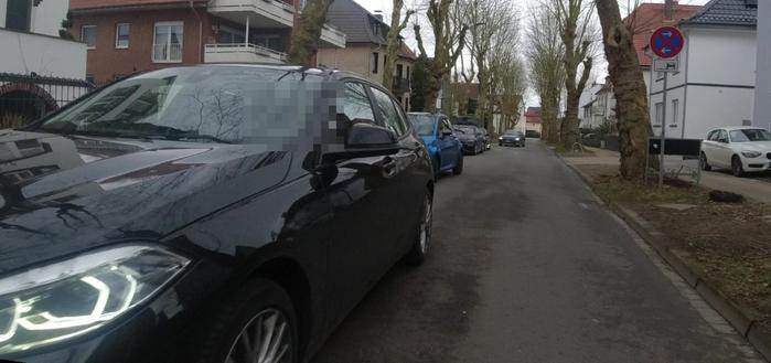 In einer Straße kommt ein Auto entgegen. Auf dessen Seite parken weitere Fahrzeuge, trotzdem wird daran vorbei gefahren und keine Rücksicht auf den vorrangigen Radverkehr genommen. Das Bild ist mit einer leicht außermittig am Lenker montierten Kamera aufgenommen.