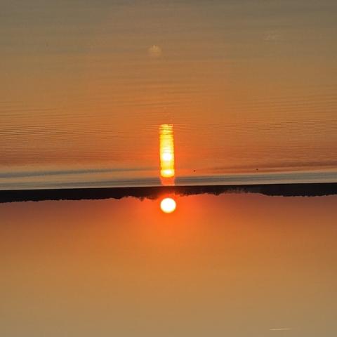 Bild eines Sonnenuntergang um 180 Grad gedreht, Spiegelung auf See sieht aus wie Ausrufezeichen