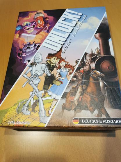 Spielschachtel unlock secret adventures - comic Wissenschaftler mit Maus, gezeichnete Dorothy mit Vogelscheuche und Blechmann, Bandit auf Pferd neben Zug