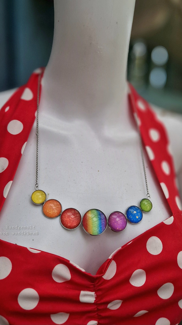Halsschmuck, groß, mit 7runden  abgestuft aneinandergereihten handgemalten unter Glas gefassten Motivfarbsteinen in Regenbogenfarben, an Schaufensterpuppte fotografiert