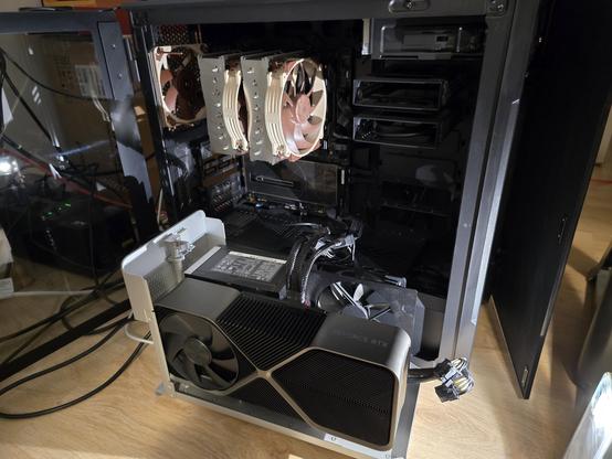 Desktop computer next to an open eGPU case with a large graphics card inside. The power supply from the desktop is connected to the external GPU