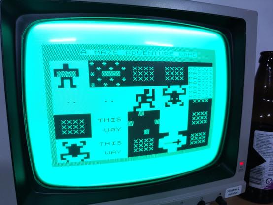 Photo of Mazogs running on my ZX80 clone computer, displaying on my green screen CRT Philips monitor.

It's the title screen of the game which shows all the main game elements, the hero, gold treasure, the monsters, the walls and even a sword.