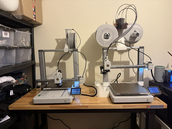 Photo of two Bambu lab a1 printers sitting side by side on a wooden worktop table