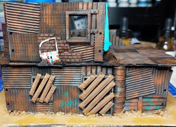 Two story shanty house made of corrugated iron boards barrels beams and bricks