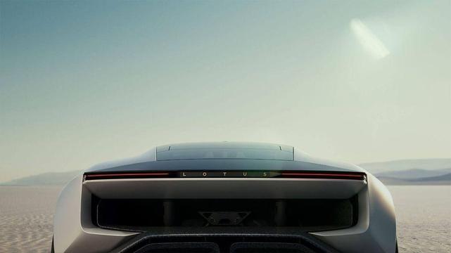 Rear view of a sleek sports car with a minimalist design, displaying the brand name "Lotus" against a desert backdrop under a clear sky.