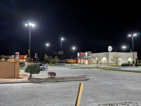 An empty parking lot and driveway showing a burger king and bojangles in the distance.