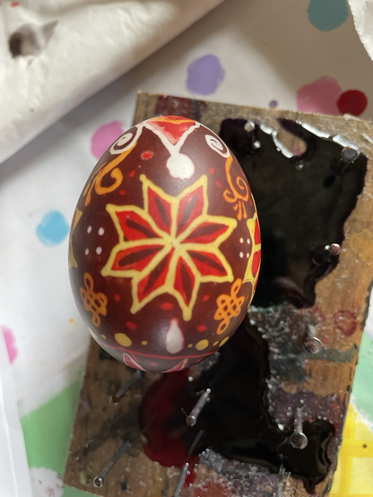 Red yellow and brown star pysanka egg with spirals, dots and knots.