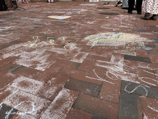 A view of sidewalk chalk art and messages across a large area of brick paving. Monsoscopic view.