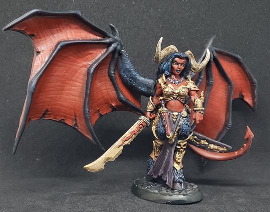 Reaper's The Queen of Hell miniature, a female demon with goat legs and horns, giant bat wings, and a big ass sword. She has red skin, black hair, and brass/gold armor and weapon.