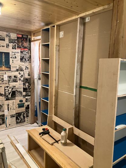 A tall narrow set of shelves being built into a wall in a cabin.