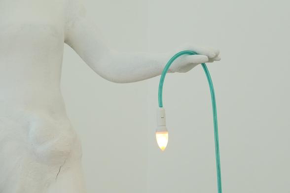 A white hand holding a green cable with a lamp at the end