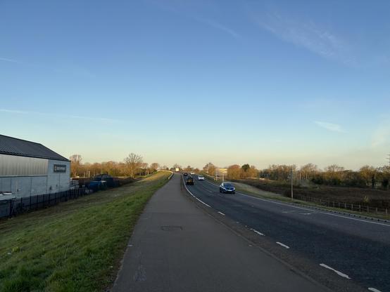 A beautiful clear blue sky above green grass… with a car-riddled road slicing through the middle.
