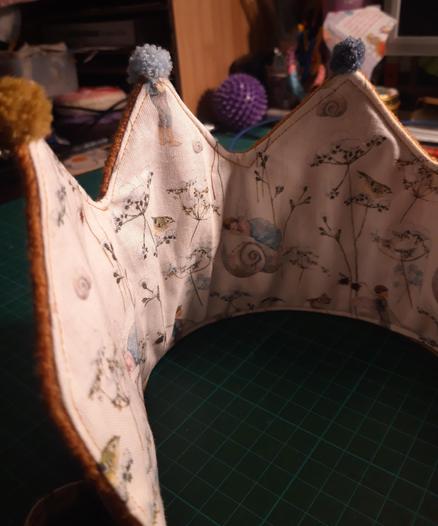 Nahaufnahme des Blickes ins innere einer Geburtstagskrone. Innen ist Baumwollwebbare mit kleinen Motiven aus Winterszenen auf weißen Stoff zu sehen.