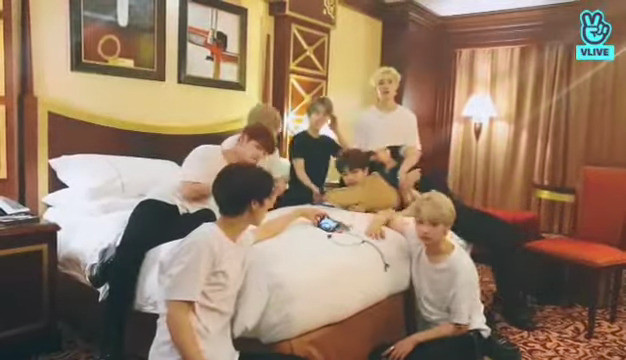 skz in a hotel room. Seungmin's bent over the bed with Chan behind him. Changbin is partially sitting on the edge of the bed but has rolled over so that his shoulders and the back of his head are helping to keep Seungmin pinned in place.