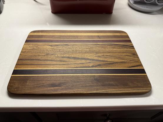 Rectangular wooden cutting board with multicolored, horizontal stripes.