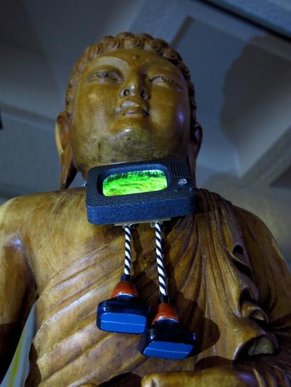 Vue rapprochée du Bouddha ou on voit le Vijou jouer de la video, avec les embouts tubes à la ligne blanche constante.