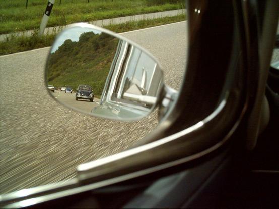 Das Bild zeigt den Seitenspiegel eines Autos, der die Straße hinter dem Fahrzeug spiegelt. Im Spiegel sind mehrere Autos zu sehen, darunter ein klassisches Volkswagen-Käfer, das direkt hinter dem Fahrzeug fährt. Die Straße ist asphaltiert und verläuft durch eine grüne Landschaft mit Hügeln im Hintergrund. Der Spiegel ist in der Nähe der Fahrertür des Autos angebracht und zeigt die Umgebung, die durch das Fenster des Fahrzeugs sichtbar ist. Die Landschaft um die Straße herum ist grün und weidet, was auf eine ländliche Umgebung hinweist. Die Spiegelung im Seitenspiegel vermittelt ein Gefühl von Bewegung und zeigt die anderen Fahrzeuge auf der Straße.

Bereitgestellt von @altbot, privat und lokal generiert mit Ovis2-8B