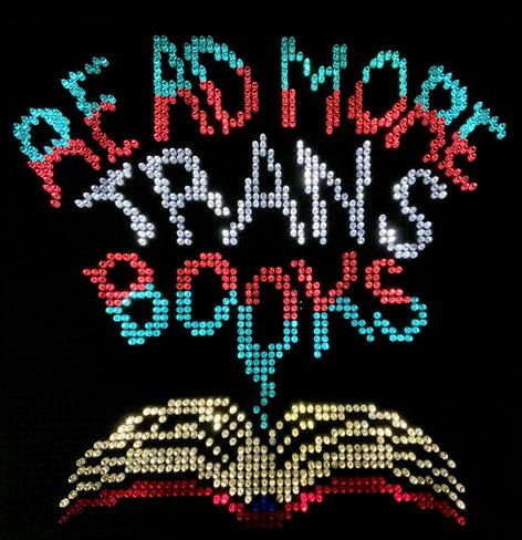 Lite brite art of an open book with words coming out of it in trans pride colors that read: "Read more trans books."