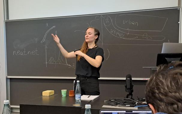 Female researcher in front of blackboard gesticulating