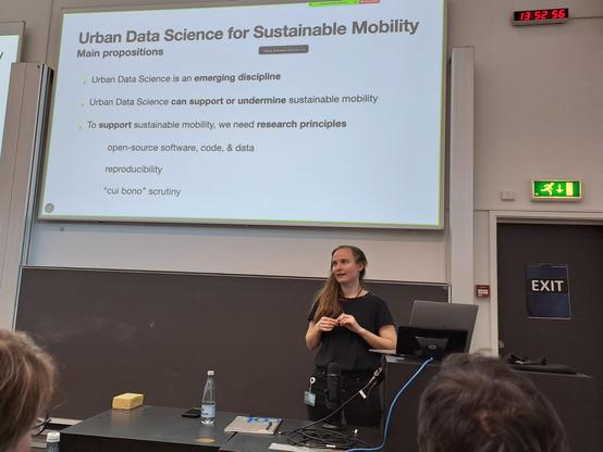 Female researcher explaining in front of slide, showing main propositions of urban data science