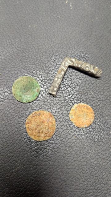 Drei alte Münzen und etwas anderes aus Metall.