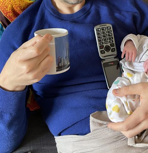 An adult holding a baby and a mug. The shot is cropped, so faces are not visible.