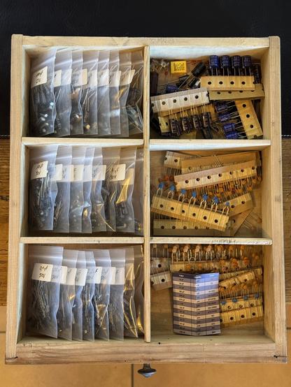 Wooden drawer filled with capacitors sorted by value in little plastic bags