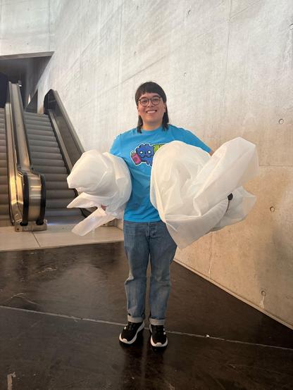 Me carrying lots of trash under my arms in front of an escalator.