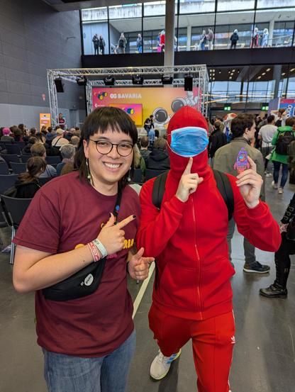 Me and a Among Us cosplayer at GGBavaria. The cosplayer is holding a Among Us themed rocket that I drew.