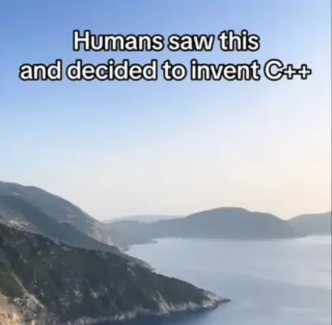 Landscape shot of mountains and ocean, with text overhead reading "Humans saw this and decided to invent C++".