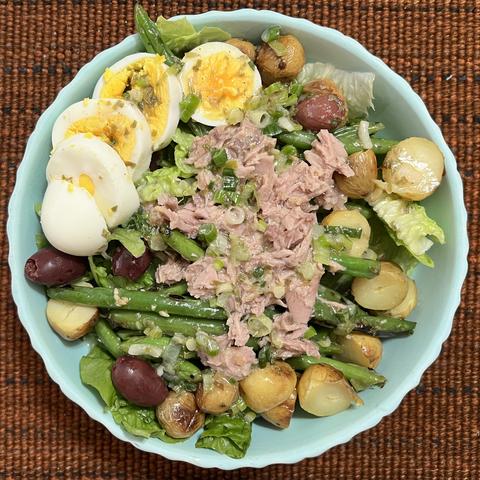 A large salad in a china bowl seen from above on a woven placemat