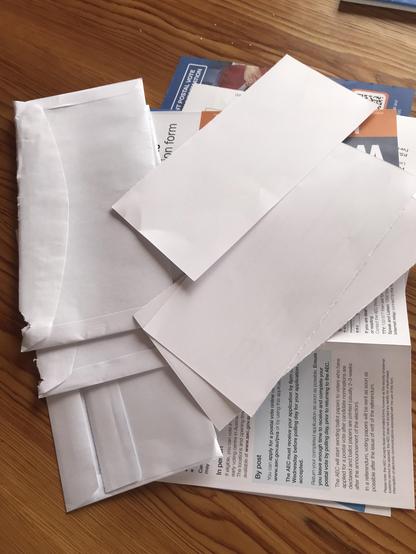 A pile of white envelopes and postal vote application forms.