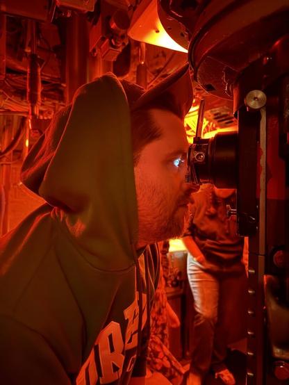 A man stares into a periscope on a submarine.